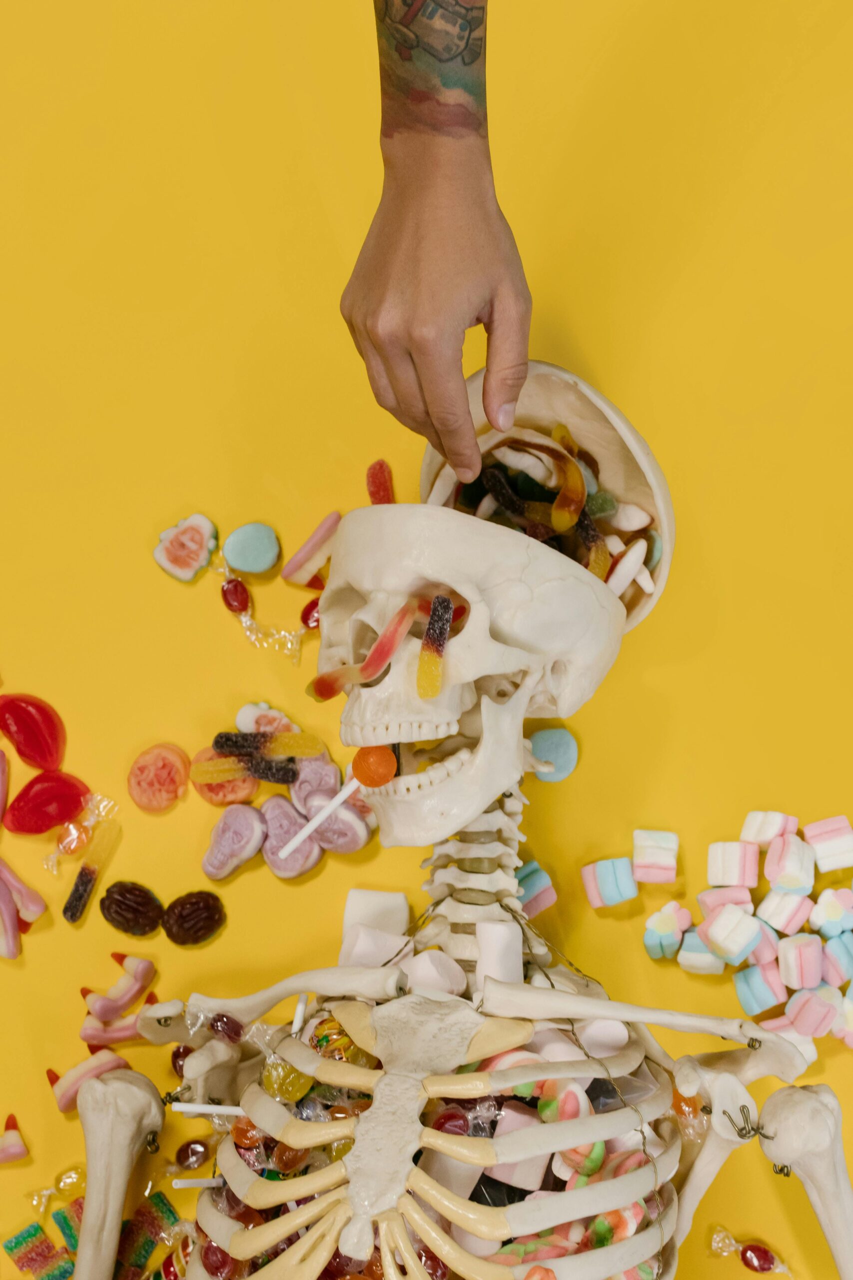 A playful Halloween setup featuring a candy-filled skeleton with a yellow backdrop. Perfect for spooky seasonal themes.